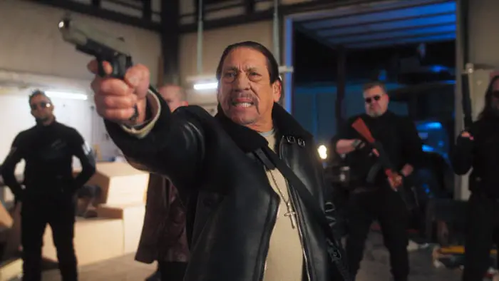 Danny Trejo as Royce aiming a handgun, surrounded by his armed crew