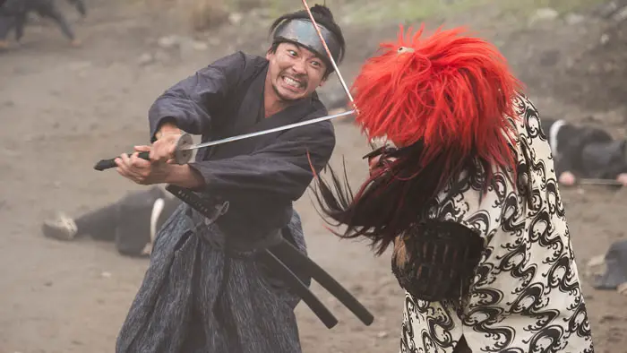 Samurai warrior clashes with masked enemy in intense sword fight from 11 Rebels