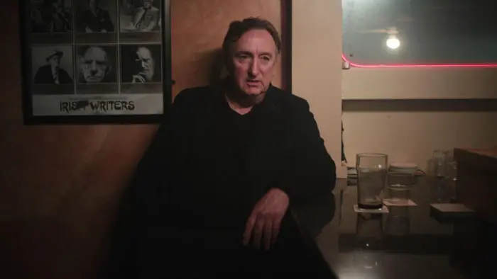 Peter Gowan sits at the bar beneath a cracked Irish Writers poster in Vanilla