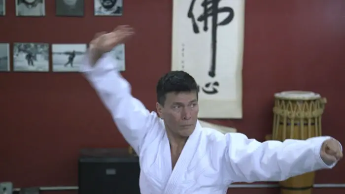  A martial arts instructor in a white gi performs a kata in a dojo