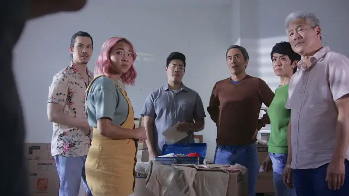 The family from No No Girl gathers around a table, reacting to the discovery of letters.