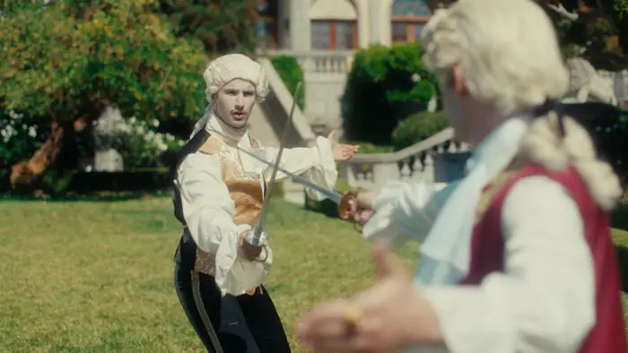 Two men in 18th-century attire engage in a dramatic fencing duel on the lawn of a noble estate