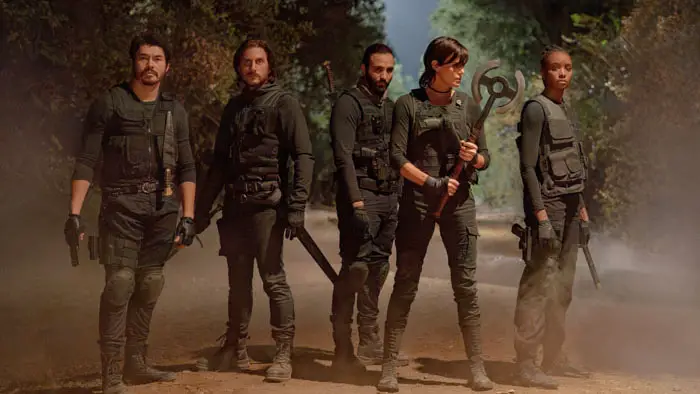 Cast of The Old Guard 2 in tactical gear walking through a forest trail