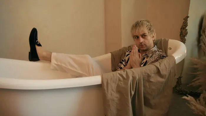 Jovan posing in a bathtub in a scene from American Comic