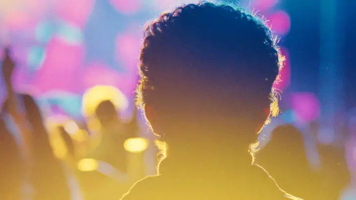 Back of DJ Ahmet’s head at a music event with colorful lights in the background.