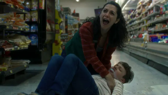 Lilly cradles a boy on the floor of a grocery store aisle, screaming in anguish