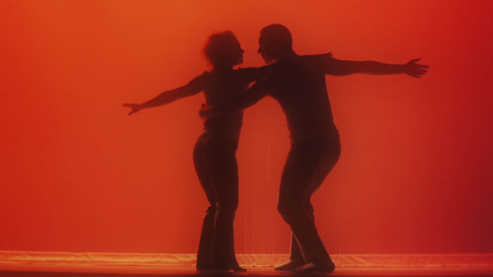 Elisa and Alex perform a contemporary dance silhouetted against a red background in Romancing Sydney.