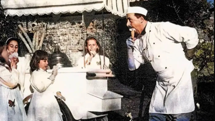Vintage photo of Sergio Dondoli as a young gelato vendor serving children.