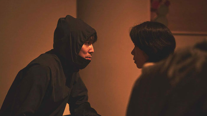 A tense face-to-face confrontation between two characters in dim lighting