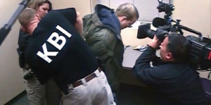 A suspect is handcuffed by law enforcement while a TV crew films during a sting operation.