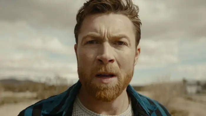 Lucas (Adam Holley) stares into the distance in the desert in Reset (2025). 