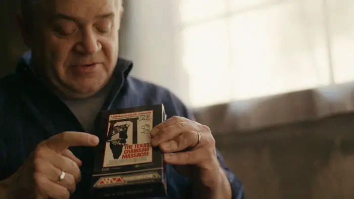 Comedian holding a vintage Texas Chain Saw Massacre VHS tape while discussing the film.
