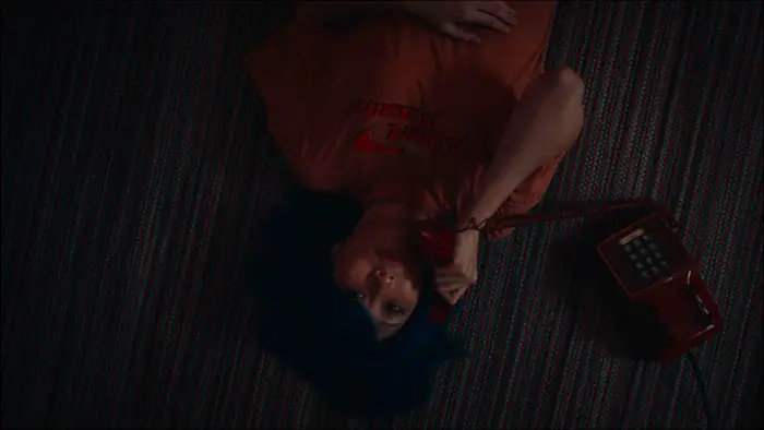 Ava Gong as Anya lying on the floor talking on a red rotary phone in Silk