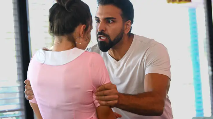A man grabs a waitress by the arms during an intense confrontation inside a diner. 