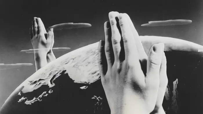 A surreal image of giant praying hands hovering over Earth from Diane Keaton’s Heaven.