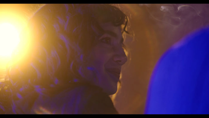 Emma smiling in warm golden light from a party scene.