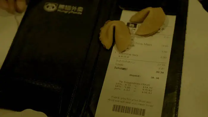 Fortune cookies resting on a restaurant bill from Nuclear Cookies