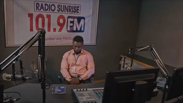 Maurice Sam as Ifiok sitting alone in the Radio Sunrise 101.9 FM broadcast studio