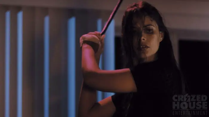 Marisol Padilla Sánchez holding a weapon in a tense scene from Transference.
