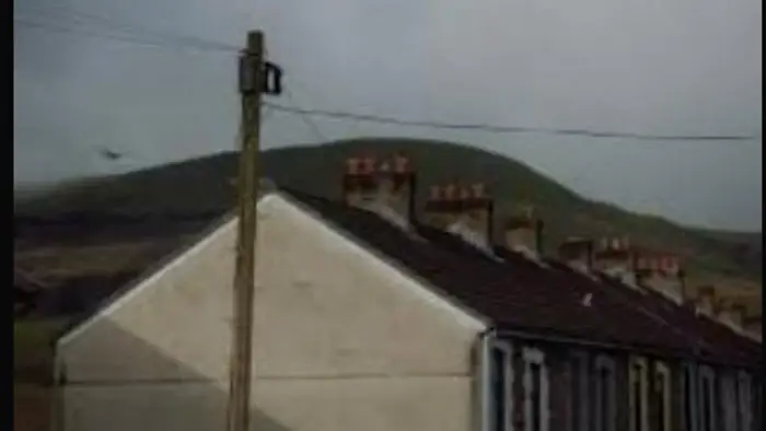 Rooftops of an isolated English village beneath misty hills in A Bear Remembers (2025).
