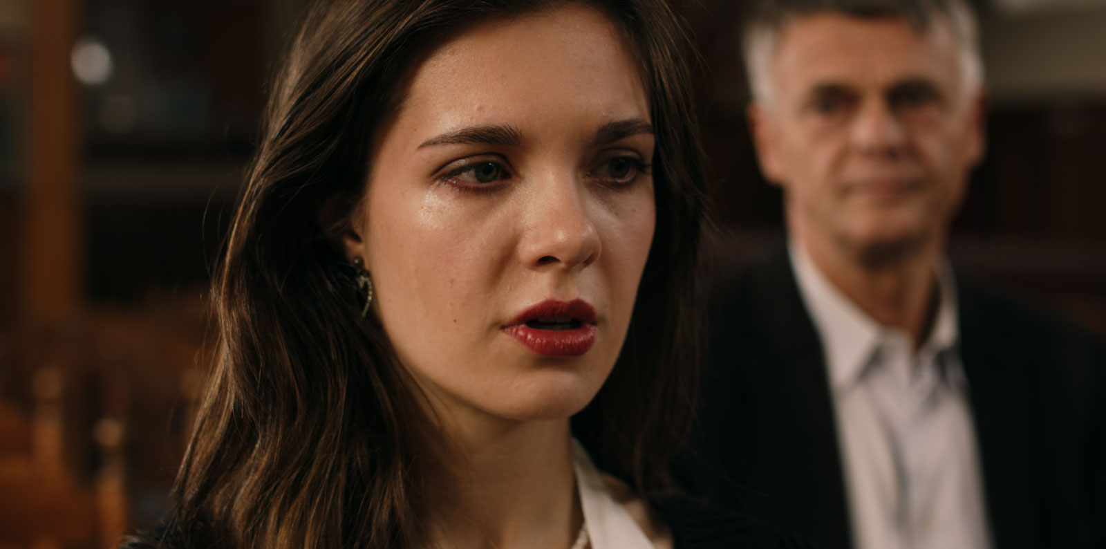 Elske Stout as Anna in an emotional close-up with Dr. Erlings blurred behind her in Diabolisch.