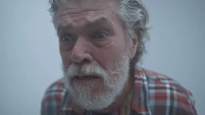 Colin Ward as Herman in Herman (2025), close-up of the isolated recluse in his cabin.