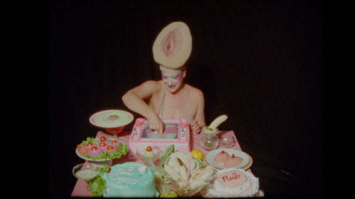 Peaches performing a surreal tableau with food, costumes, and playful sexual imagery in Peaches Goes Bananas.