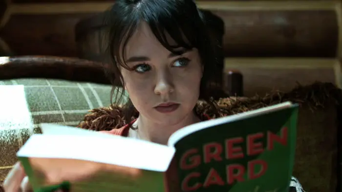 Mary (Lyndsey Bentham) reads a book titled “Green Card” in Seclusion (2025).
