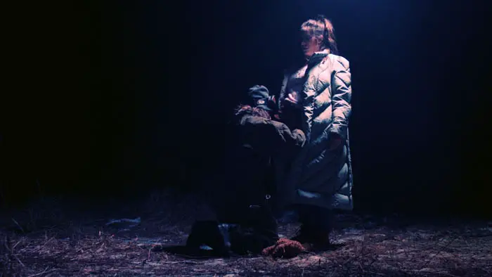 Amelia is confronted by a mysterious woman in the woods during a nighttime attack in Something of a Monster.