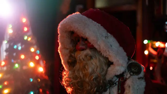 A dimly lit Santa figure stands beside a glowing Christmas tree in The Specter of Christmas.