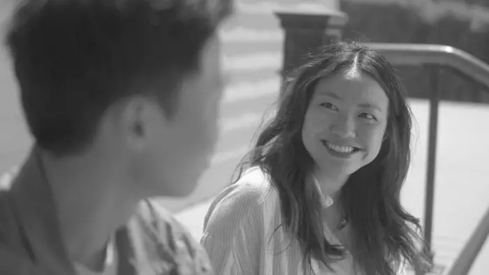 Black-and-white still from Walter Kim’s Banana Split with Alice (Jessica Chung) smiling at Peter (Min-Gu) outdoors in New York City. 