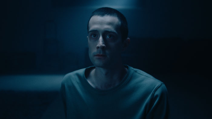 Max Wren (Nicholas Jaquinot) sits in blue light in a tense moment in Lenore (2025).
