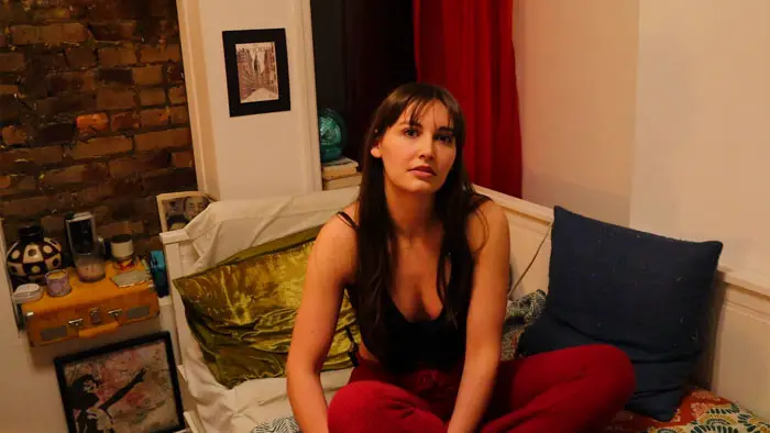 Marissa Peterson (Allison Sonson) lounges on a bed holding a drink as she films her audition videos in My Submission (2026).