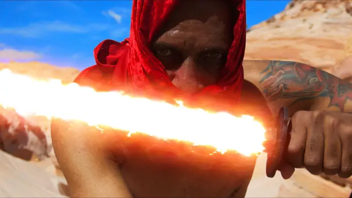 Red-hooded figure holds a flaming blade in a desert landscape in Out Of Darkness: Heavy Is The Crown (Vol. 1).