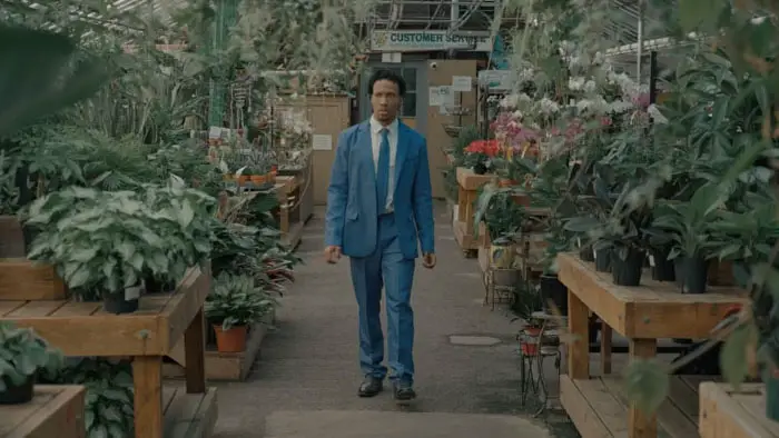 Christon Andell as Niles walking through a greenhouse of experimental plants in Purple Haze (2026)