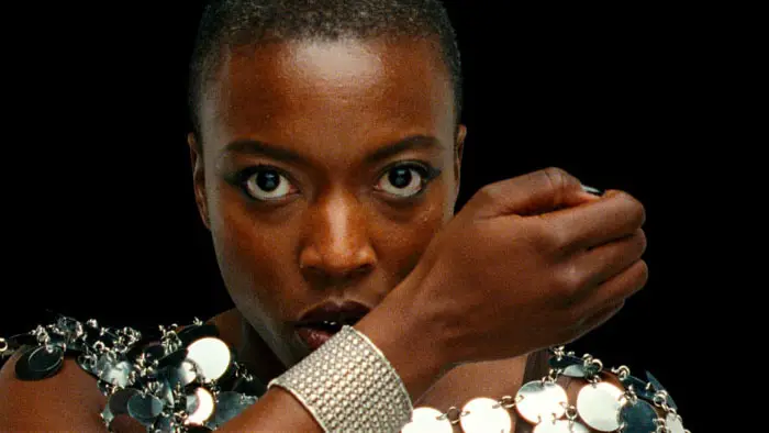 Celine Camara in Reflection in a Dead Diamond (2025), close-up with intense stare and glittering metallic accessories.