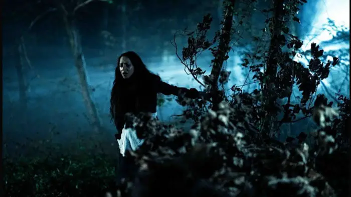 Hannah (Devon Ross) moves through a dark forest at night in Vindicta