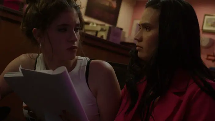 Gloria Schwarber (Olivia Gropp) and Lulu LaRue (Raleigh Tabora) rehearse lines in a late-night diner scene from Gloria’s Cut (2026).