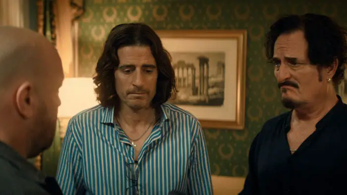 Matt Taylor (Kevin James) speaks with two men in a hotel room in Solo Mio (2026). 