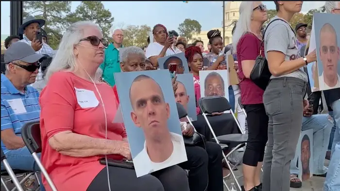Community members hold photos of incarcerated victims during a vigil in The Alabama Solution documentary