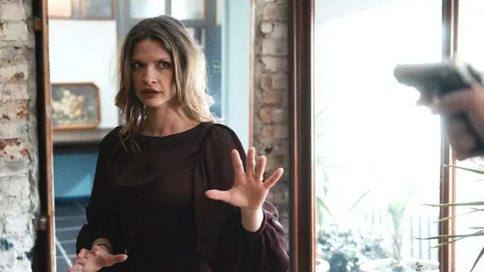 Syama Rayner as Ester confronted at gunpoint in The Art of Telling Lies (2026)