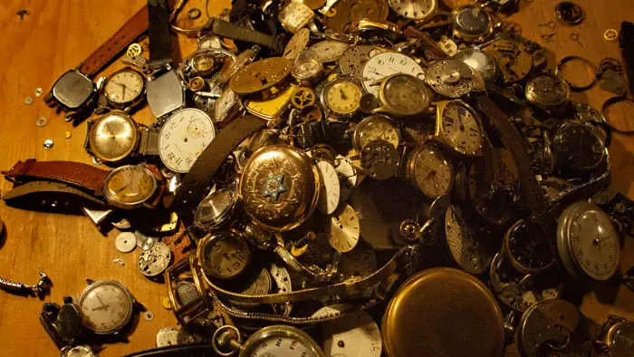 A pile of pocket watches and watch parts on a work surface in Watching Walter.