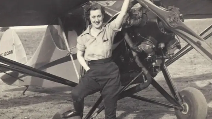 Nadine Ramsey posing beside an aircraft during her early aviation career in The WASPS: Taking Flight.